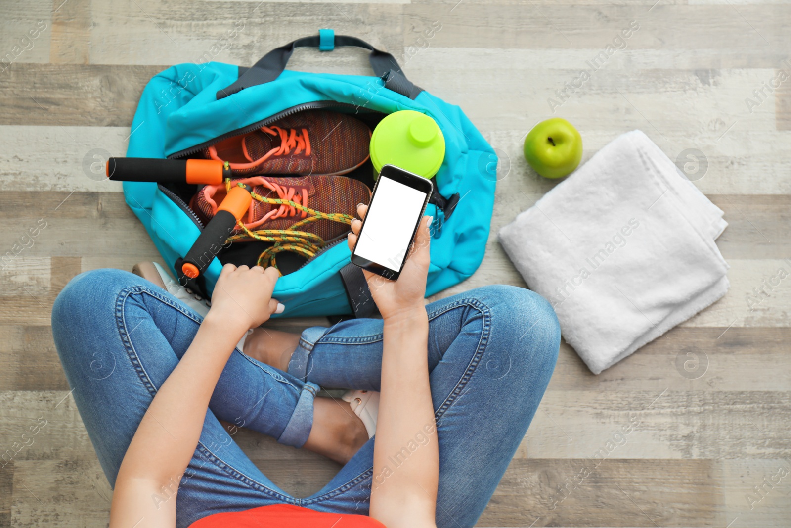 Photo of Young woman packing sports bag on floor, top view