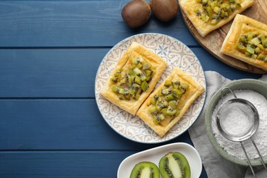 Fresh tasty puff pastry with kiwi served on blue wooden table, flat lay. Space for text