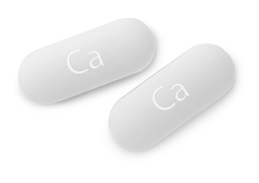 Photo of Two calcium supplement pills on white background, flat lay