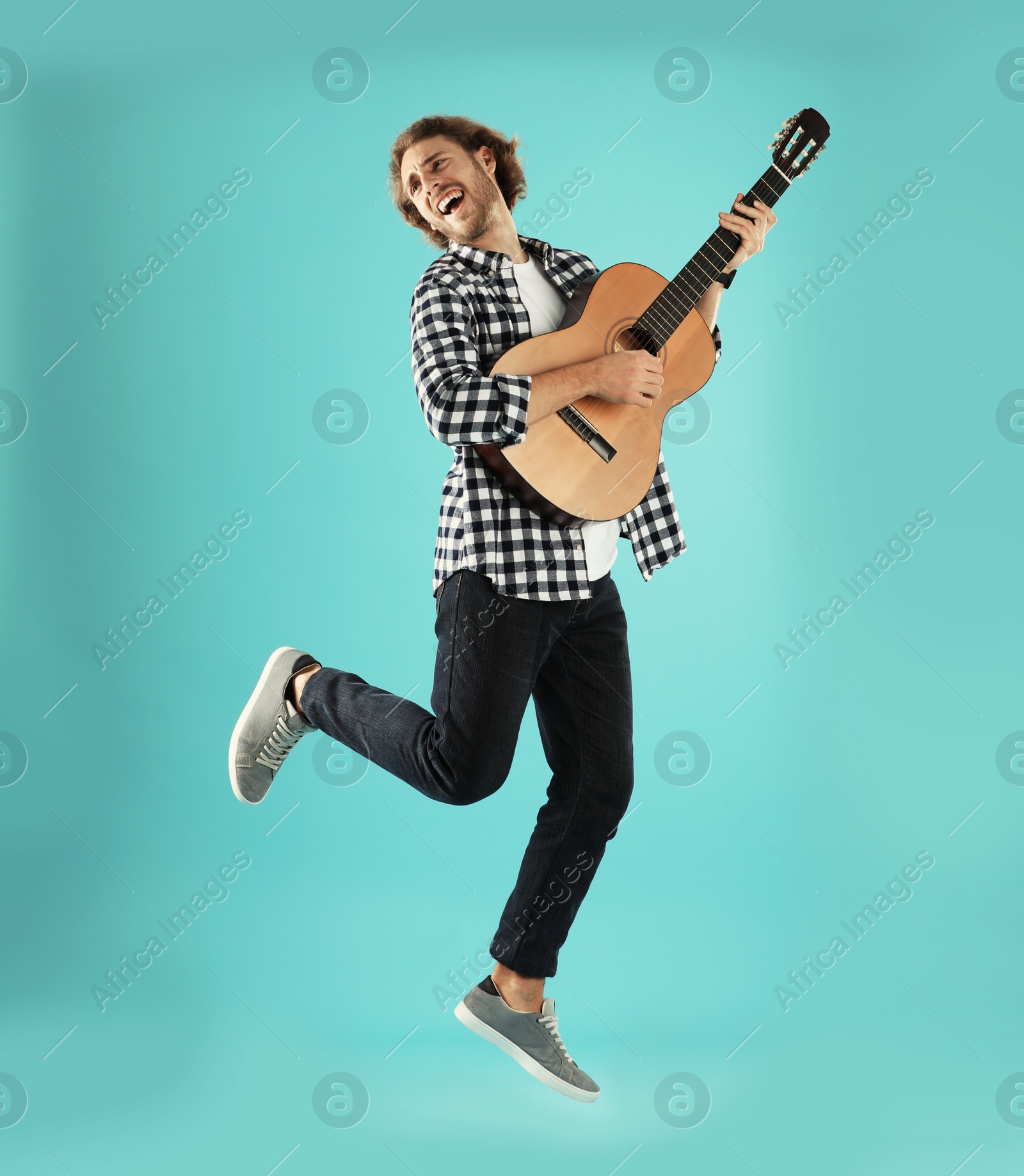 Photo of Young man playing acoustic guitar on color background