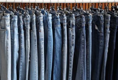 Photo of Rack with different jeans on wooden background