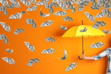 Woman holding yellow umbrella under money rain on color background, closeup 