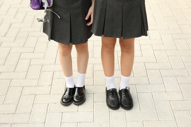 Photo of Girls in stylish school uniform outdoors, focus on legs