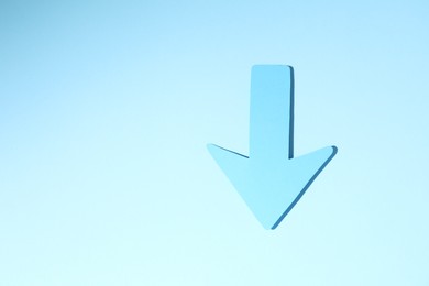 Photo of One paper arrow on light blue background, top view. Space for text