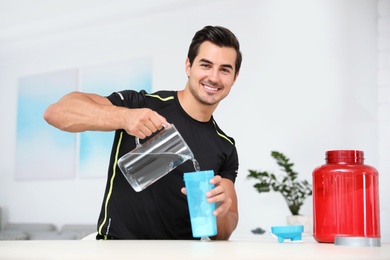 Photo of Young athletic man preparing protein shake at home