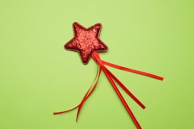 Photo of Beautiful red magic wand on light green background, top view
