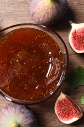 Photo of Glass bowl with tasty sweet jam and fresh figs on wooden table, flat lay