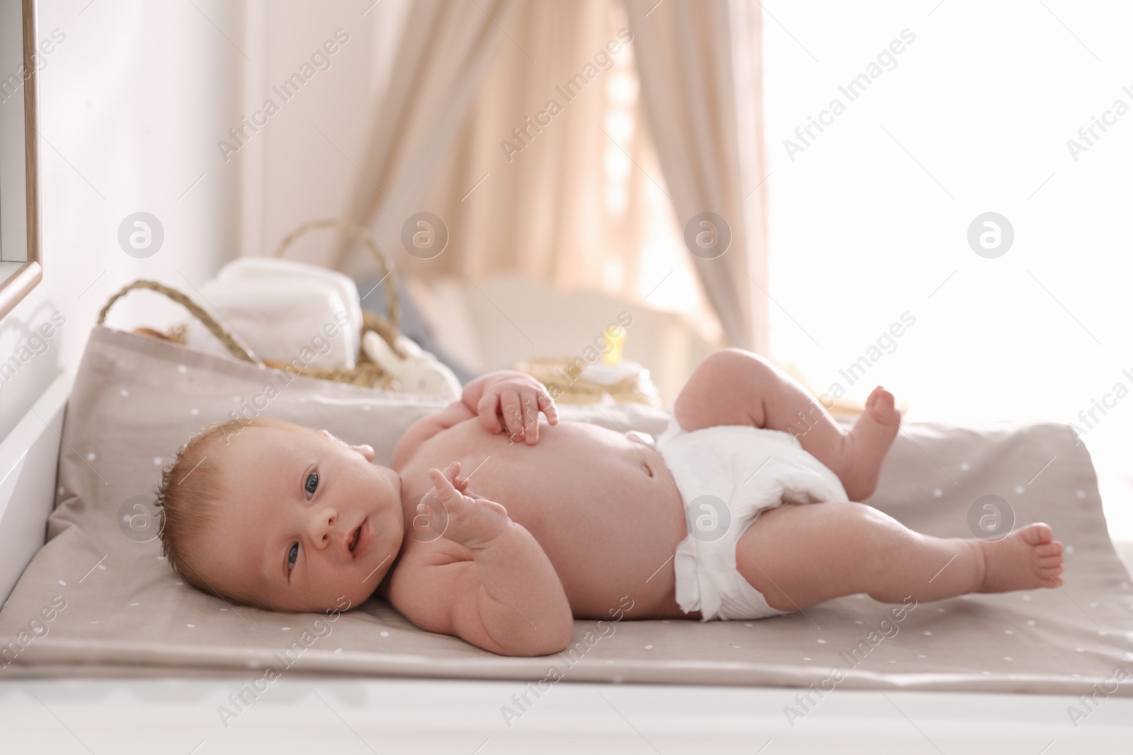 Photo of Cute little baby on changing table in room