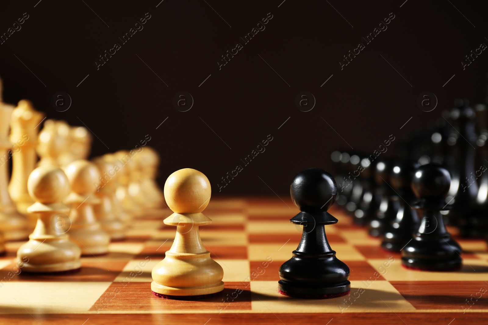 Photo of Chess pieces on wooden board against dark background. Competition concept