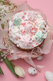 Traditional Easter cake with meringues and painted eggs on pink background, above view