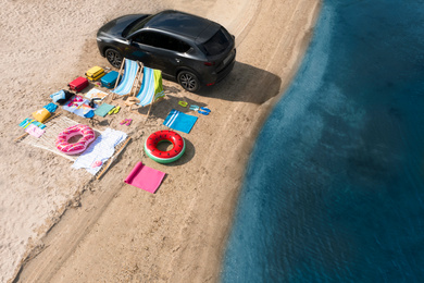 Car and beach accessories on sand near river, aerial view. Summer trip
