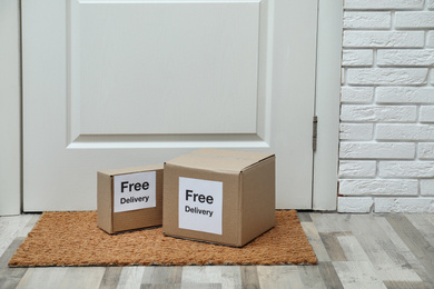 Photo of Parcels with stickers Free Delivery on rug indoors. Courier service