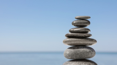 Photo of Stack of stones against blurred seascape, space for text. Zen concept