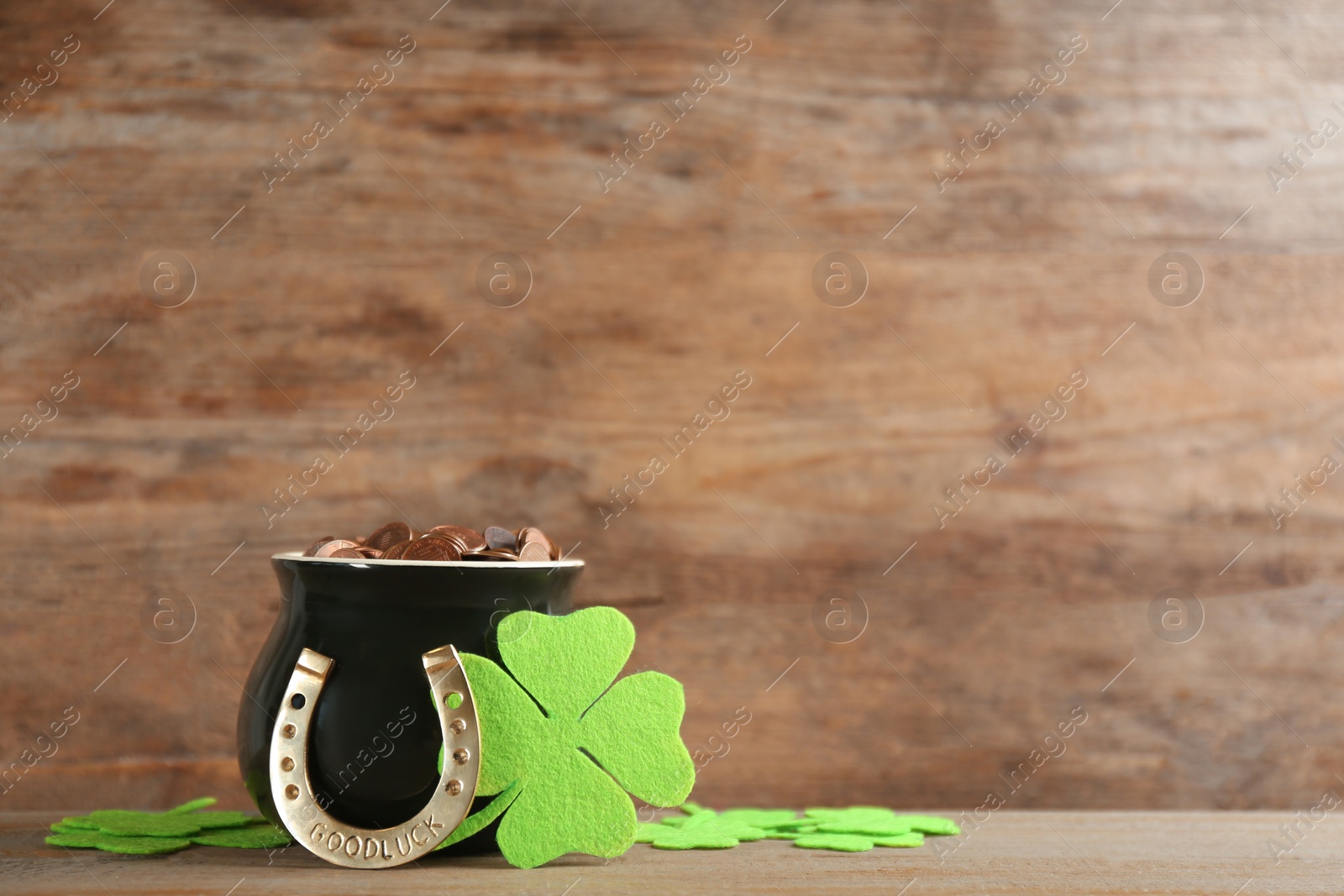 Photo of Pot of gold coins, horseshoe and clover leaves on wooden table, space for text. St. Patrick's Day celebration