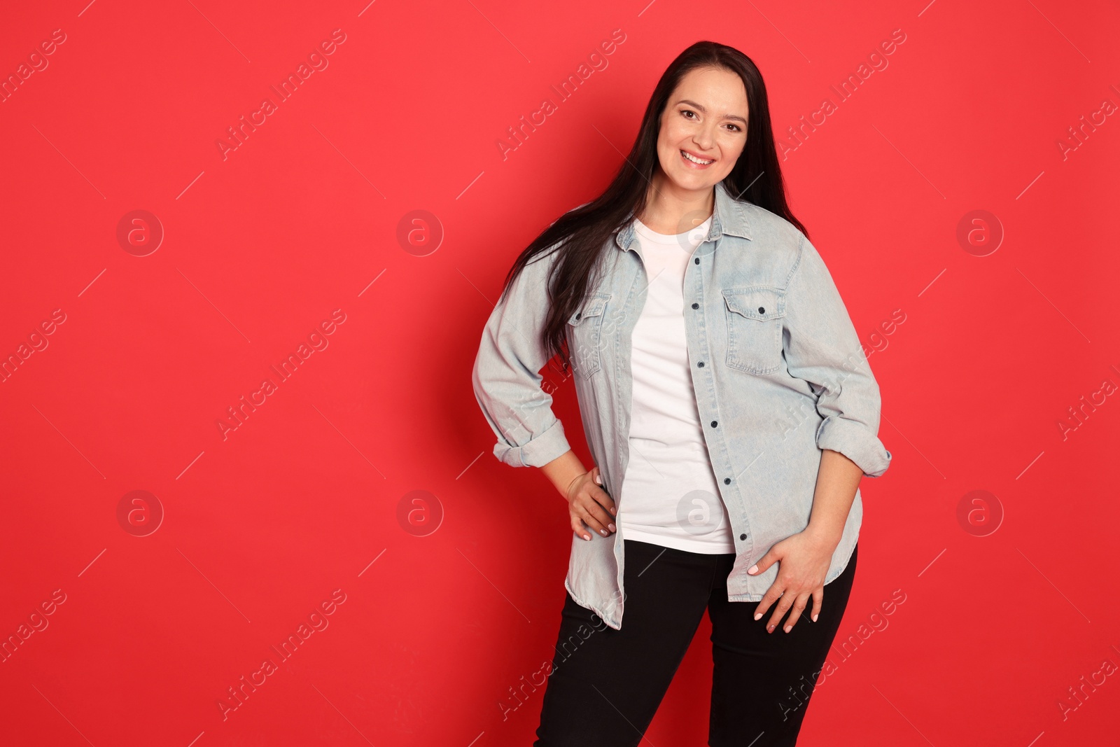 Photo of Beautiful overweight woman with charming smile on red background. Space for text