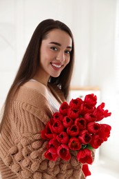 Photo of Happy woman with red tulip bouquet at home. 8th of March celebration