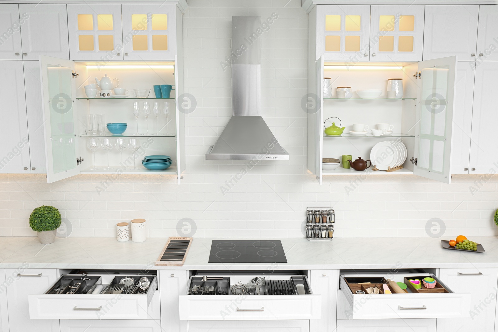 Photo of Open cabinets with different clean tableware and utensils in kitchen