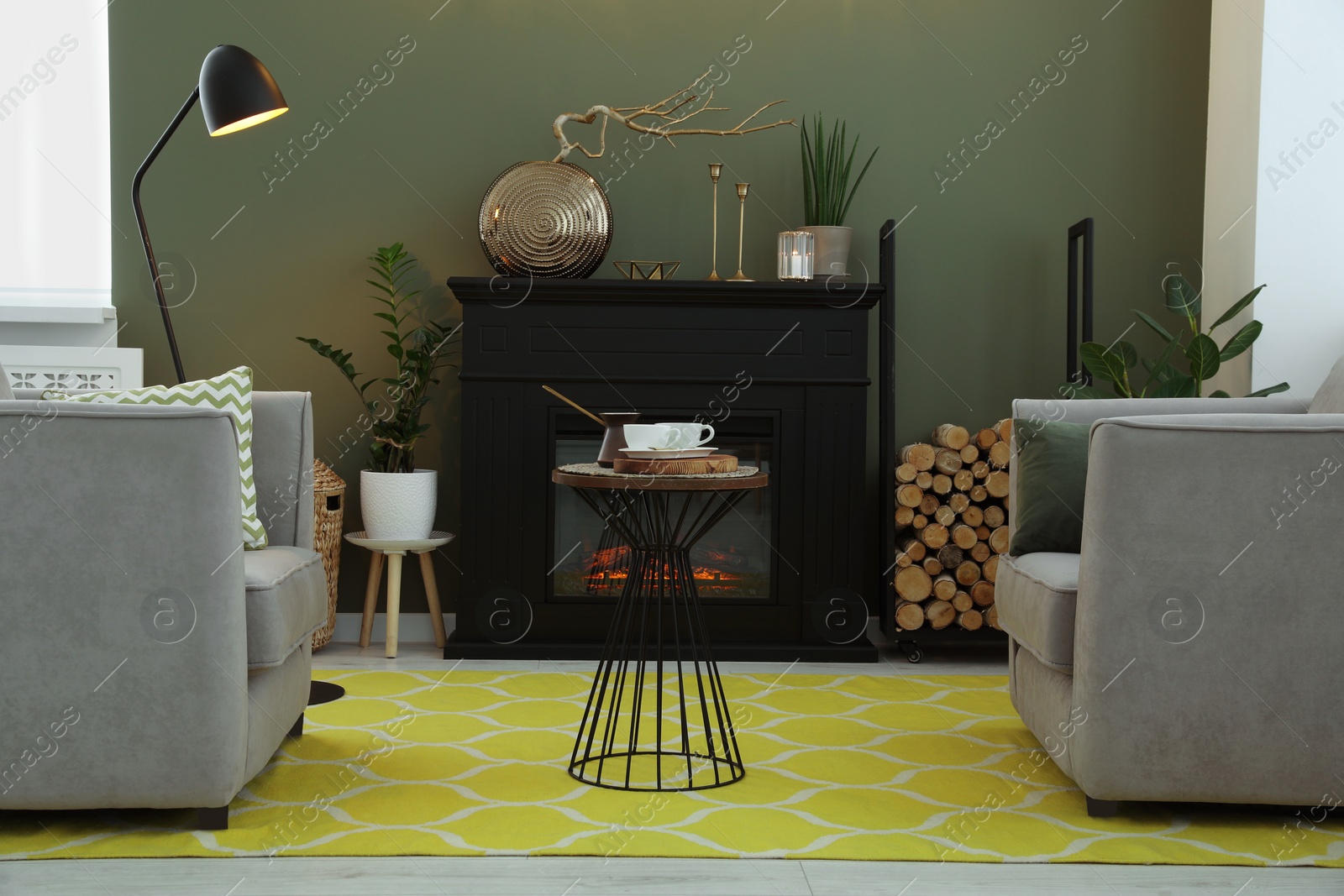 Photo of Beautiful fireplace, armchairs, table and different decor in living room. Interior design