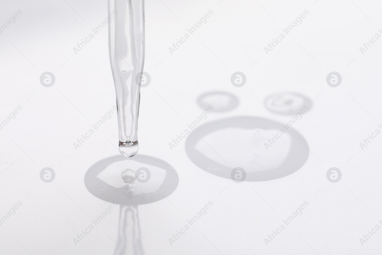 Photo of Glass pipette and transparent liquid on white background, closeup