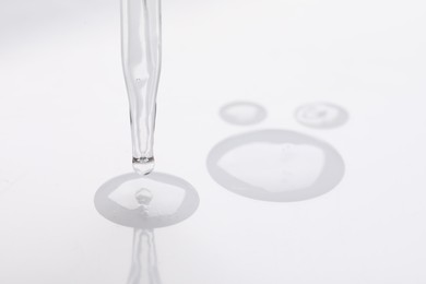 Glass pipette and transparent liquid on white background, closeup