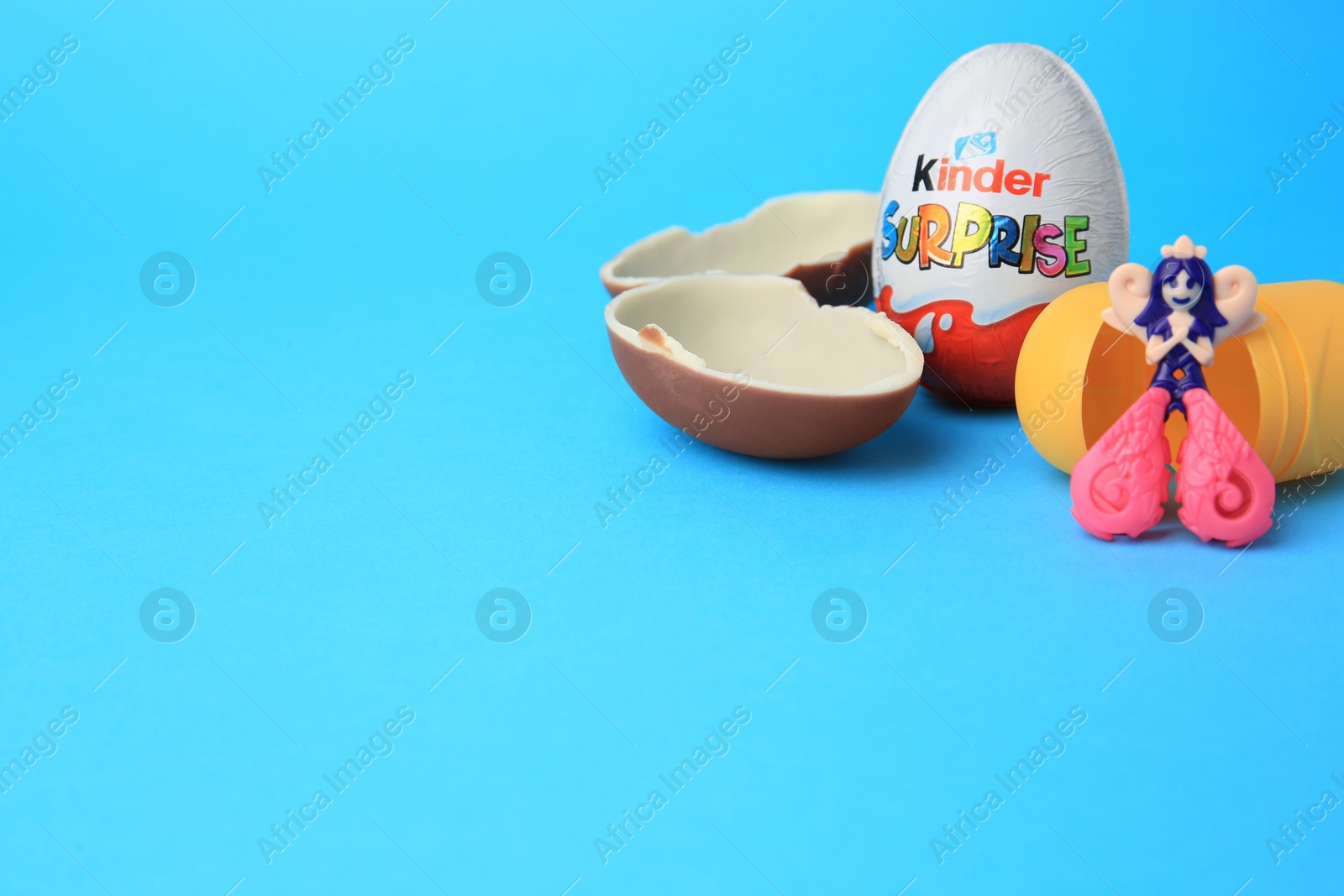 Photo of Slynchev Bryag, Bulgaria - May 25, 2023: Kinder Surprise Eggs, plastic capsule and toy on light blue background, space for text