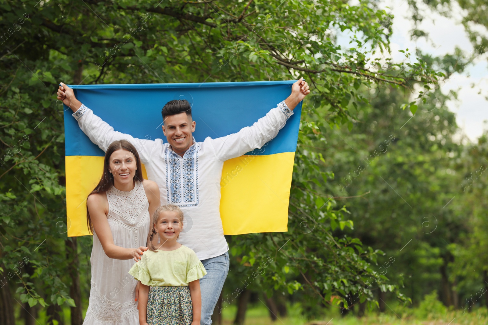 Photo of Happy family with national flag of Ukraine outdoors
