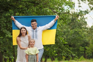 Happy family with national flag of Ukraine outdoors