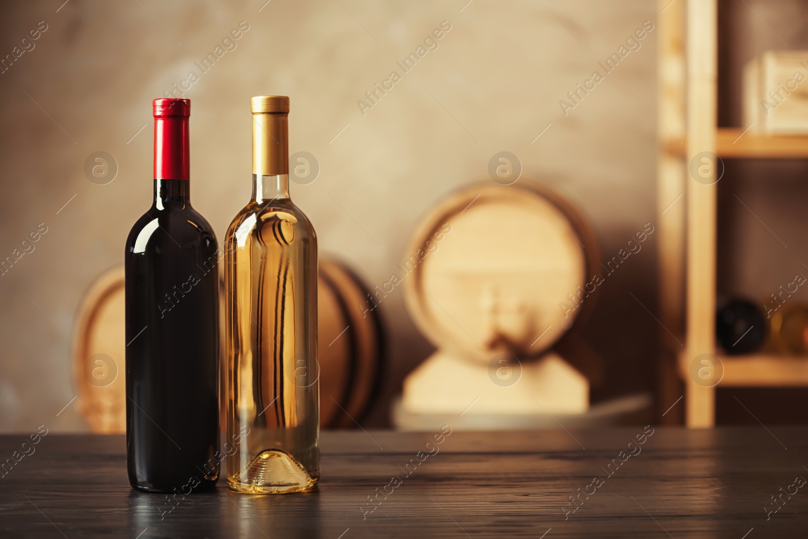 Photo of Bottles of delicious wine and blurred barrels on background