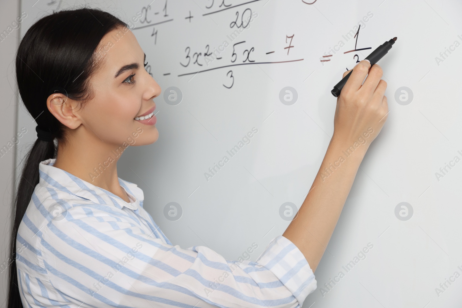 Photo of Happy teacher explaining mathematics at whiteboard in classroom