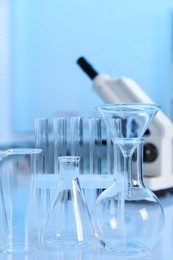 Photo of Laboratory analysis. Different glassware and microscope on white table indoors