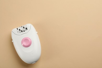 Photo of Modern epilator on beige background, top view. Space for text