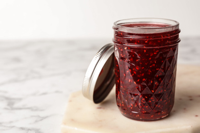 Photo of Delicious raspberry jam on marble table. Space for text