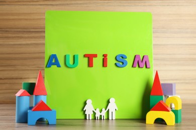 Magnetic board with word Autism, family figure and wooden blocks on table