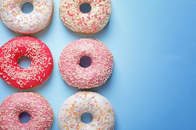 Photo of Delicious glazed doughnuts on color background, top view