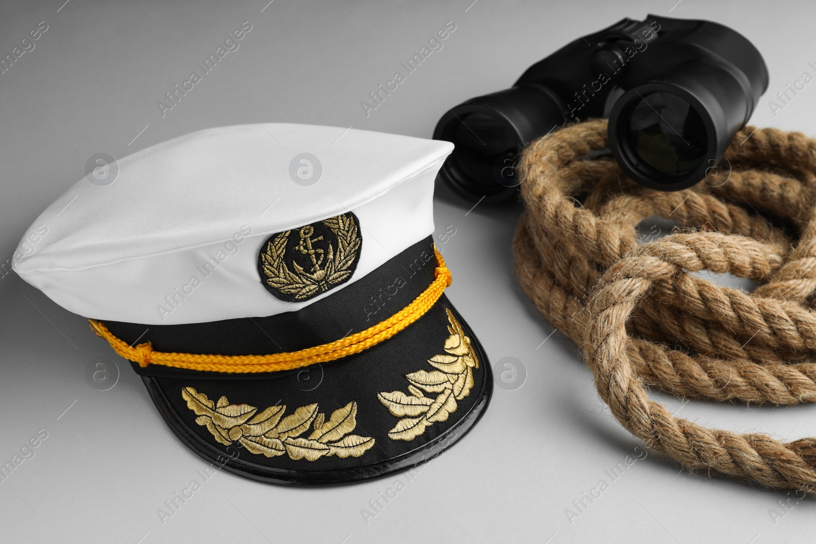 Photo of Peaked cap, rope and binoculars on light grey background