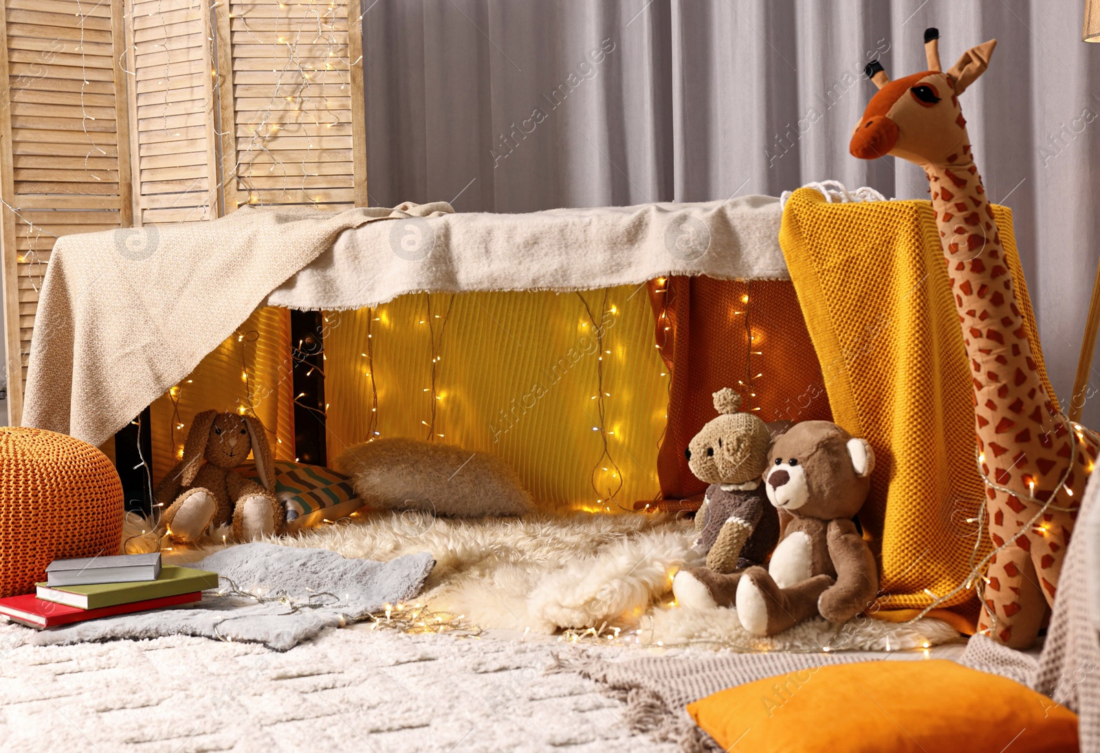 Photo of Beautiful play tent decorated with festive lights and toys at home