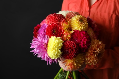 Photo of Woman with bouquet of beautiful dahlia flowers on black background, closeup