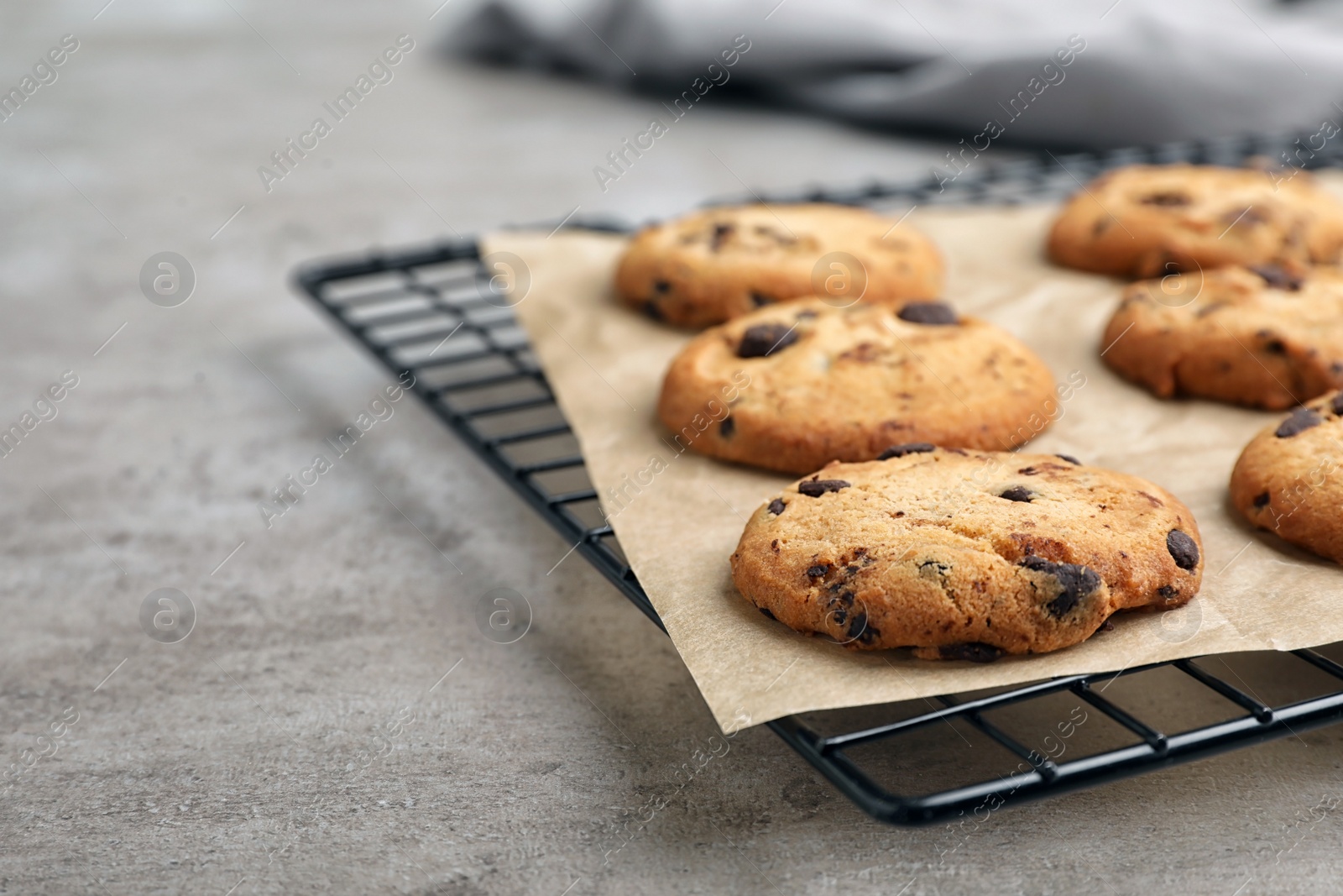 Photo of Cooling rack with tasty chocolate cookies on gray table