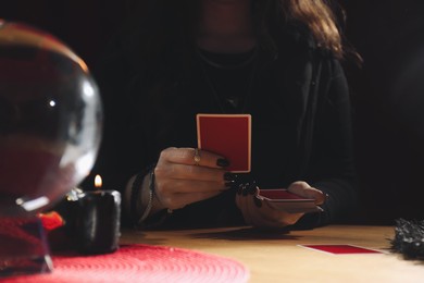 Photo of Soothsayer predicting future with cards at table indoors, closeup