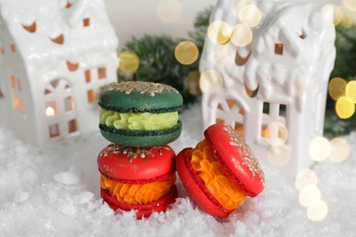 Photo of Different decorated Christmas macarons on table with artificial snow