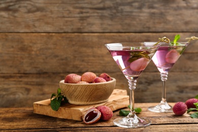 Lychee cocktail on wooden table, space for text