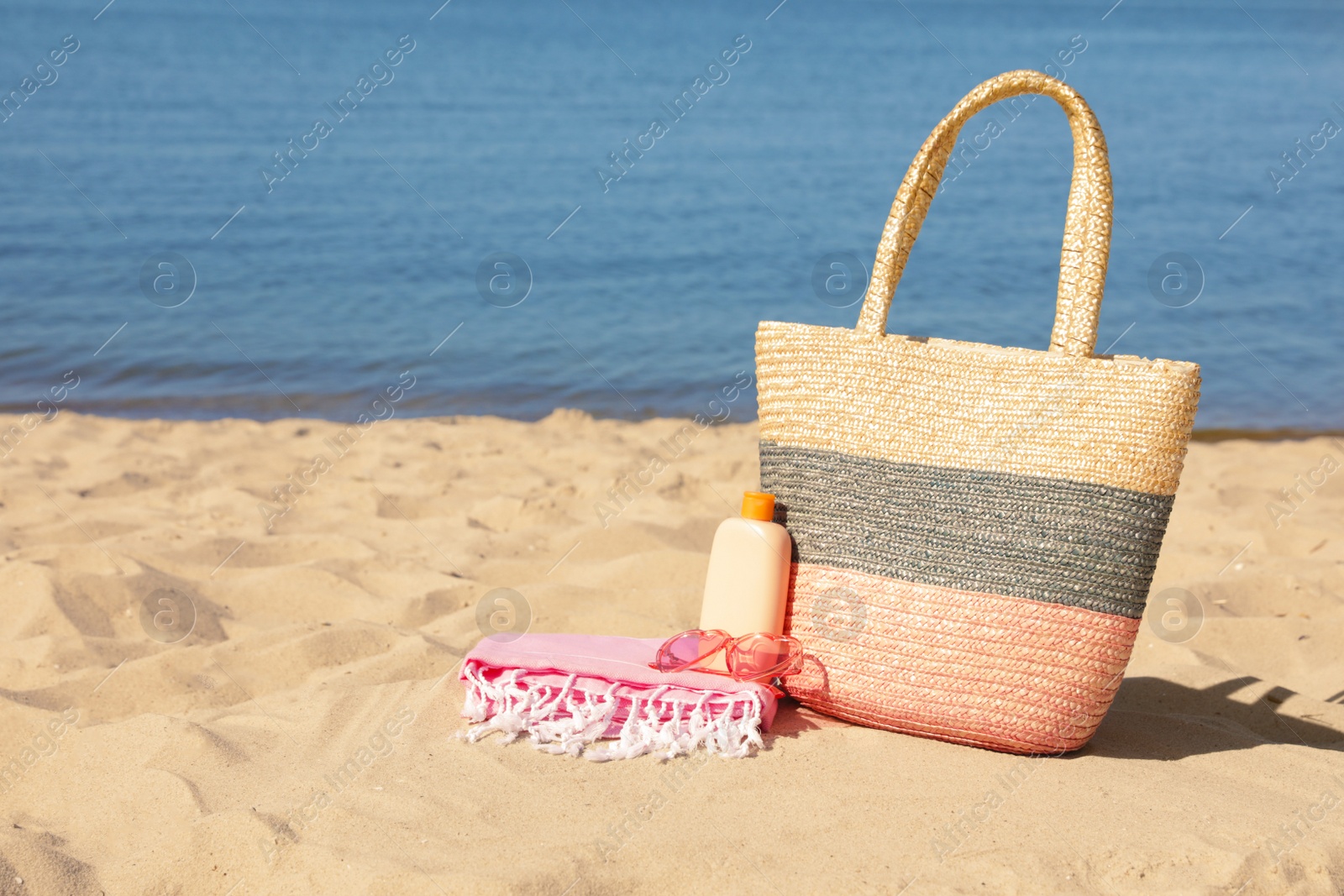 Photo of Stylish beach accessories on sand near sea. Space for text