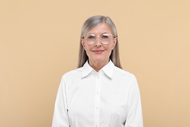 Photo of Portrait of beautiful senior woman in glasses on beige background