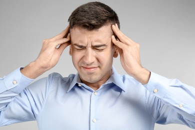 Photo of Young man suffering from headache on light background