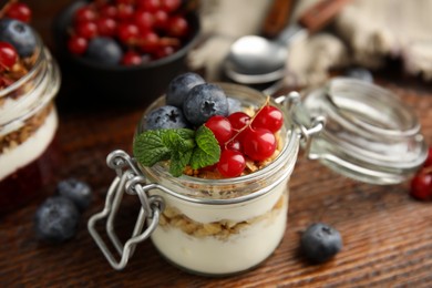 Photo of Delicious yogurt parfait with fresh berries and mint on wooden table, closeup