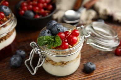 Delicious yogurt parfait with fresh berries and mint on wooden table, closeup