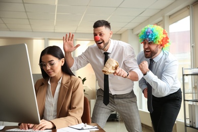 Photo of Men popping paper bag behind their colleague in office. Funny joke