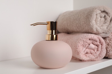 Stylish soap dispenser and towels on shelf