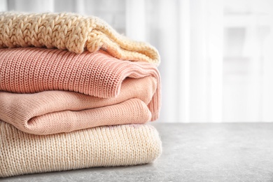 Photo of Stack of warm knitted clothes on table