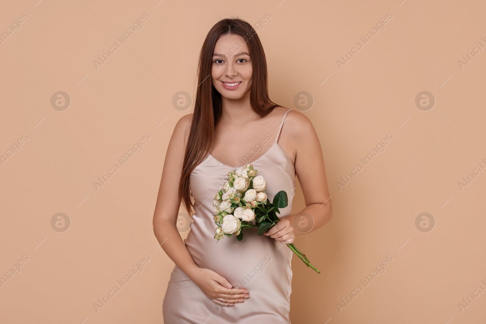 Photo of Beautiful pregnant woman in dress with bouquet of roses on beige background